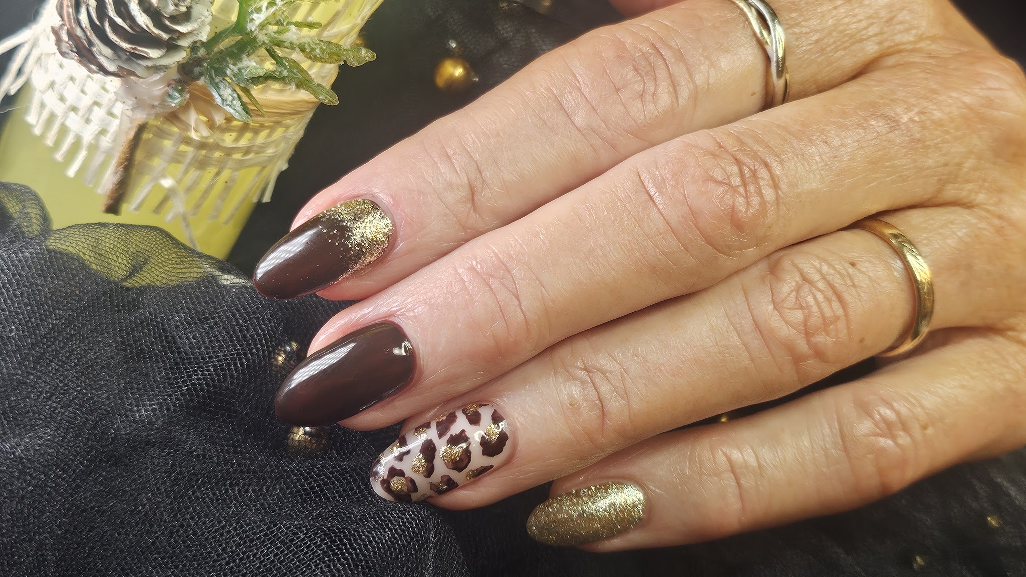 Donkerbruine nagels met goudglitter en een nagel met luipaardprint